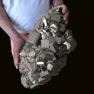 Very large pyrite with striated cubic crystals, held vertically to show its scale.